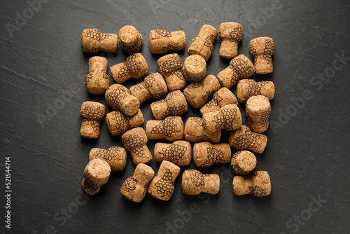 Sparkling wine corks with grape images on black table, flat lay