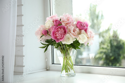 Beautiful peony bouquet in vase on windowsill indoors