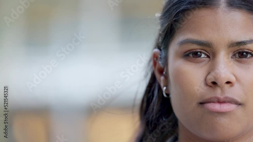 Young woman looking confident, serious and focused while standing outside against blurred background with copy space. Closeup face and head of a young female posing expressionless with copyspace