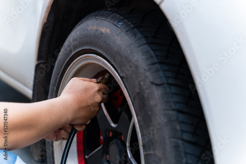 Close up of man filling air in the tires of his car. Hand and car wheel add air pressure. © banphote