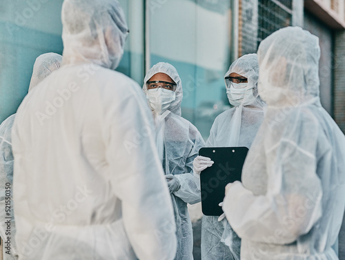 Health and safety personnel in protective gear ready to fight a virus, outbreak or pandemic. Hazmat wearing doctor, nurse and team or group of medical and healthcare professional at a quarantine site