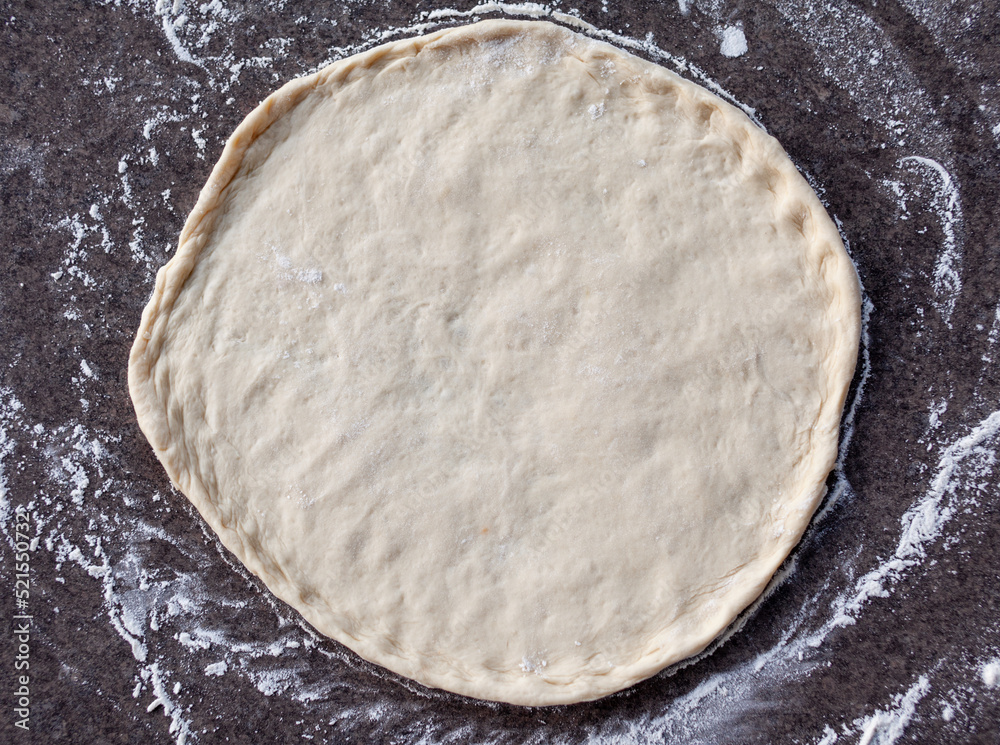 Rolled out pizza dough on floured slate surface, photographed overhead with natural light Rolled out pizza dough on floured slate surface, photographed overhead with natural light