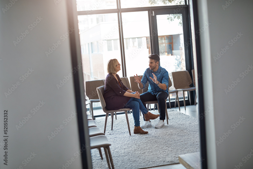 Young businessman talking to his therapist after a therapy meeting at a psychology office for mental health problems. Male employee having a discussion with a mature woman in a modern boardroom Young businessman talking to his therapist after a therapy meeting at a psychology office for mental health problems. Male employee having a discussion with a mature woman in a modern boardroom