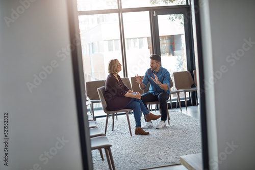 Young businessman talking to his therapist after a therapy meeting at a psychology office for mental health problems. Male employee having a discussion with a mature woman in a modern boardroom