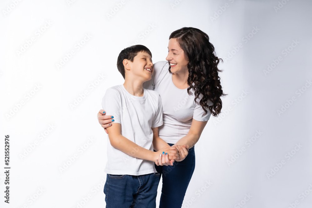 mother and son hug, communicate. models in white t-shirts, blue jeans. White background mother and son hug, communicate. models in white t-shirts, blue jeans. White background
