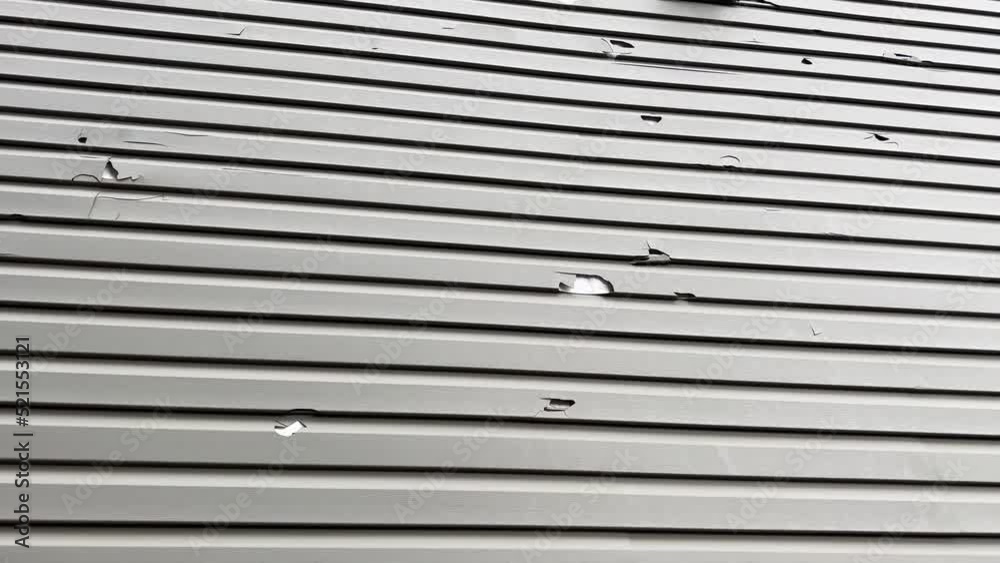Holes in the exterior siding of the home from hail storm damage. The