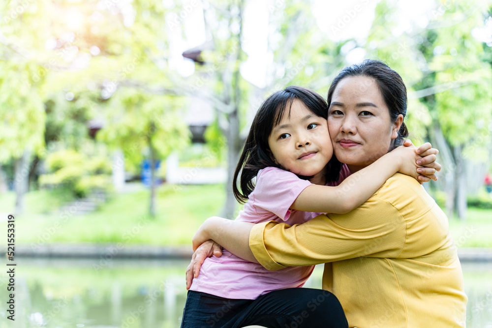 Cute young daughter with her mother hugging in love playing together in a park Cute young daughter with her mother hugging in love playing together in a park