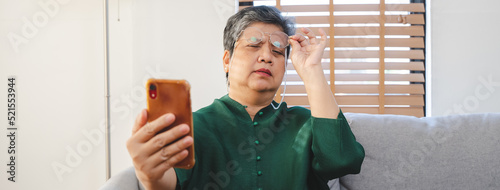 Mature asian woman have eyesight focus problem during reading text in mobile phone. photo
