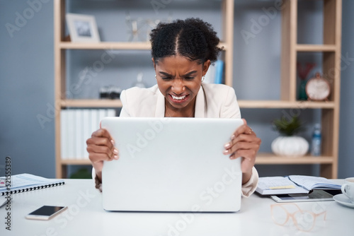 Frustrated, angry and stressed young business woman on a laptop in a modern office. Female showing anger with technology at the workplace. Lady employee grabbing computer due to slow connection photo