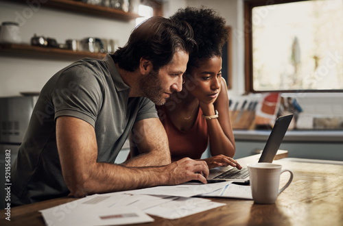 Couple with a laptop doing finance paper work, paying debt insurance loans or online ebanking together at home. Two serious people planning and looking at financial document, bills rate for mortgage photo