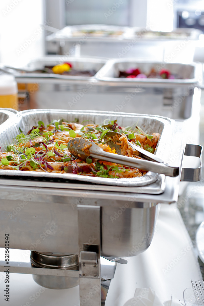 Ταπετσαρία A view of several chafer dishes filled with savory entrees, seen at a local catered event