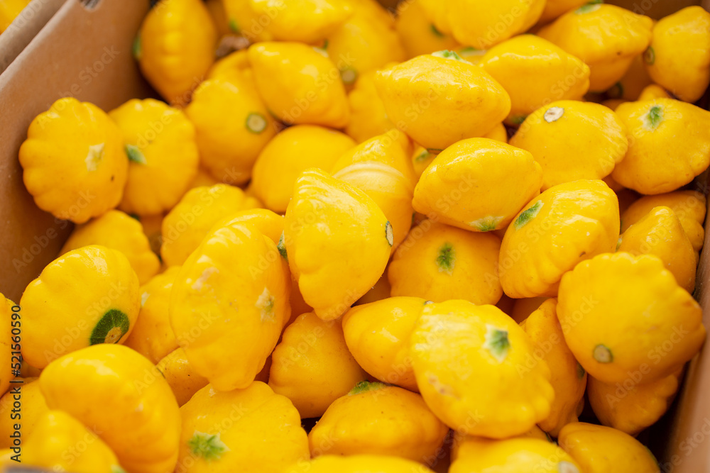 A view of a box full of yellow pattypan squash, on display at a local farmers market.