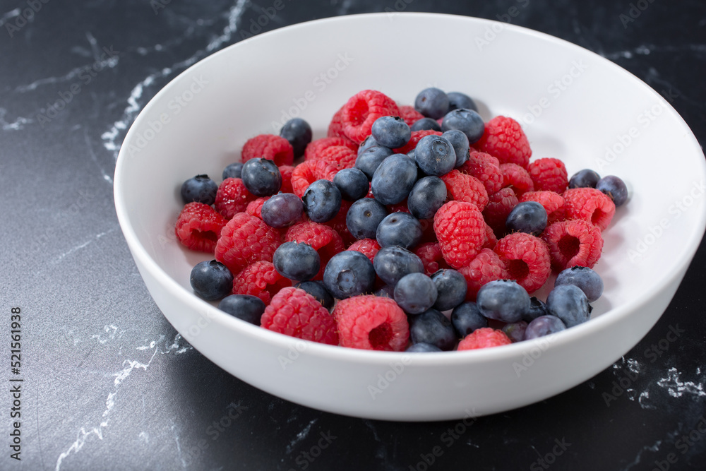 A view of a bowl of berries, featuring blueberries and raspberries. A view of a bowl of berries, featuring blueberries and raspberries.