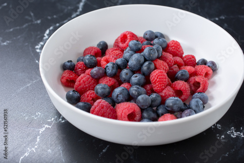 A view of a bowl of berries  featuring blueberries and raspberries.