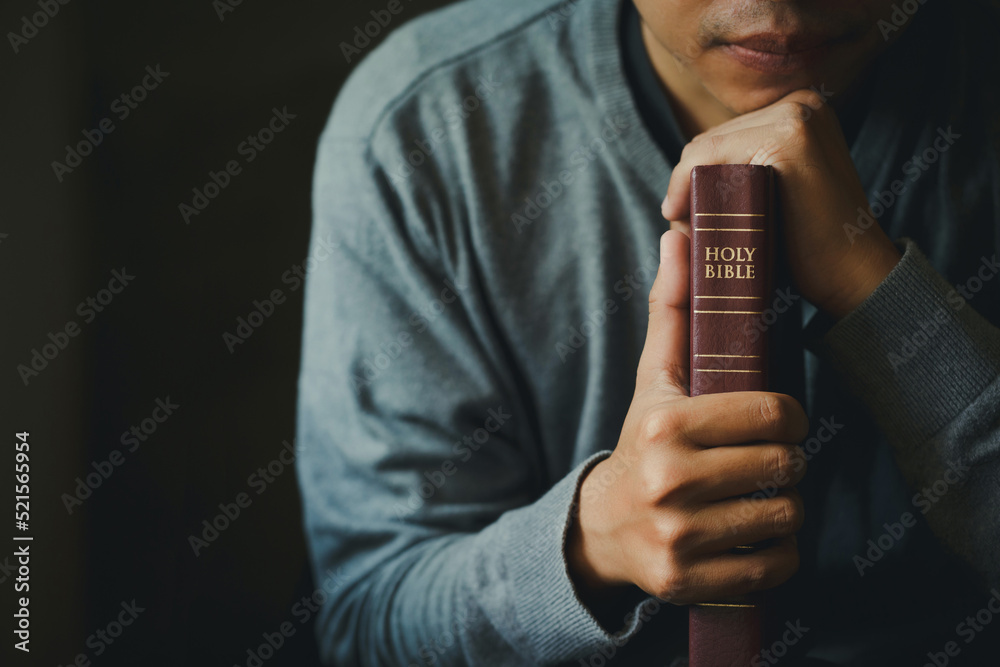 Man praying on the holy bible in the morning. Man hand with Bible praying, Hands folded in prayer on Holy Bible in church concept for faith, spirituality, religion.Christian life crisis prayer to god. Man praying on the holy bible in the morning. Man hand with Bible praying, Hands folded in prayer on Holy Bible in church concept for faith, spirituality, religion.Christian life crisis prayer to god.