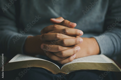 Fotografiet Man praying hands clasped together on  Bible