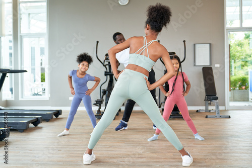 Trainer woman is leading African American family workout exercise in sport club   Healthy and wellbeing life concept