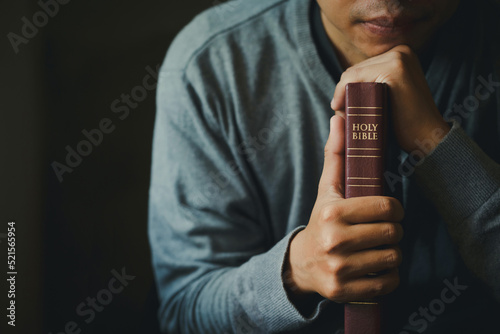 Man praying on the holy bible in the morning. Man hand with Bible praying, Hands folded in prayer on Holy Bible in church concept for faith, spirituality, religion.Christian life crisis prayer to god.