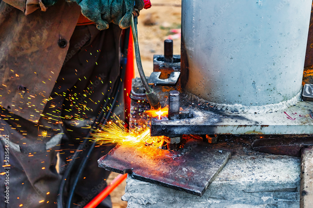 Worker cutting metal plate by Gas Cutting Torch at a construction site