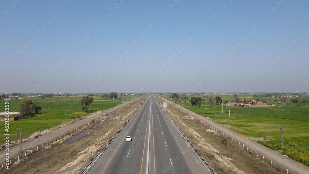 An aerial image of Lahore-Sialkot Motorway on a clear sunny day with some moving vehicles, Punjab Province, Pakistan. 