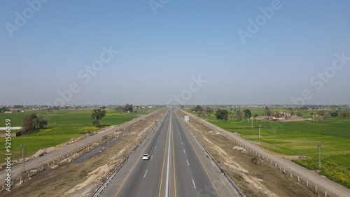 An aerial image of Lahore-Sialkot Motorway on a clear sunny day with some moving vehicles, Punjab Province, Pakistan. 