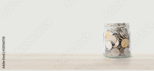 Large quantity of  Thai baht coins in glass jar,color toned in clean pastel. Saving money concept.
