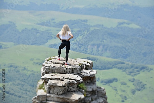 a girl on top of a rock looks at the mountains of the North Caucasus. Bermamyt Plateau. The concept of rest  vacation  freedom