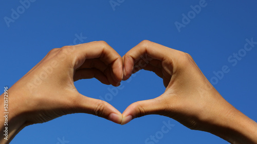 joined hands forming a heart on the blue sky in the background