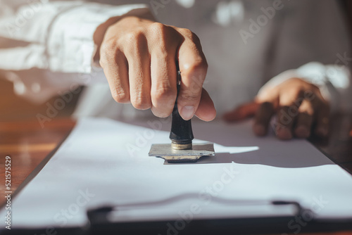 Tableau sur toile Close up of business hand stamping approved on certificate document in office, Lawyer stamping permit on paperwork at wooden desk