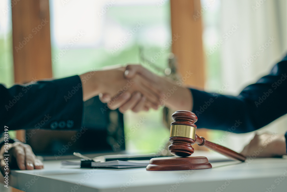 Close-up view of a lawyer holding a client's hand, making an agreement, signing a contract, a side judge's hammer and brass scales. Law offices, law and justice consulting services Close-up view of a lawyer holding a client's hand, making an agreement, signing a contract, a side judge's hammer and brass scales. Law offices, law and justice consulting services