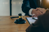 Close-up view of a lawyer holding a client's hand, making an agreement, signing a contract, a side judge's hammer and brass scales. Law offices, law and justice consulting services