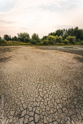 Drought and climate change, landscape of cracked earth with orange sky after lake has dried up in summer. Water crisis an impact of global warming.
