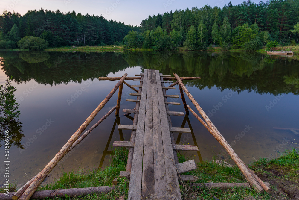 Wooden jumping pier at the small forest lake