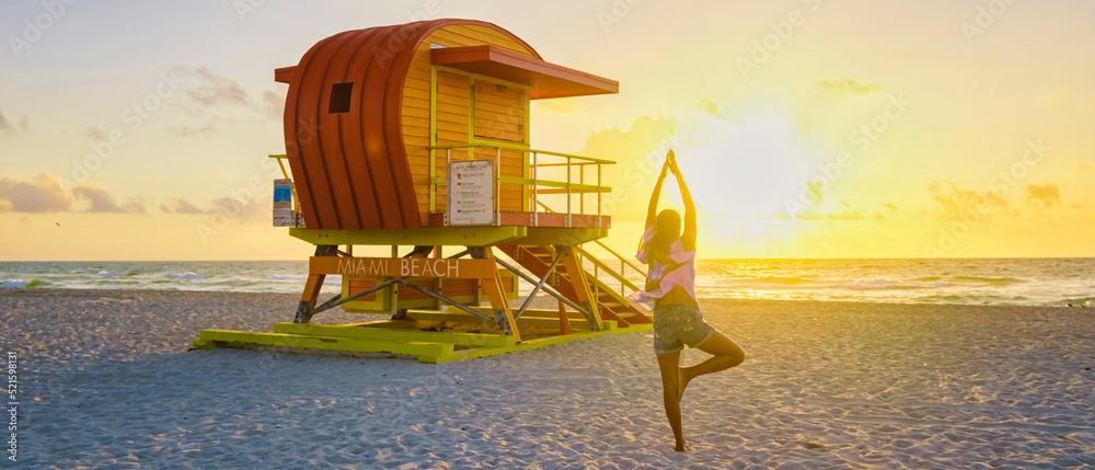 Obraz premium Asian women doing yoga during sunrise on the beach at Miami Florida South Beach. people doing yoga in the morning