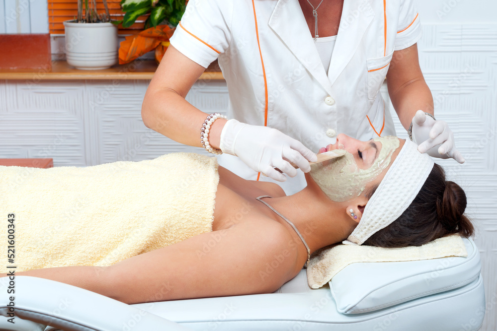 Fototapeta premium Girl with facial mask lying in beauty health spa center and getting professional skincare treatment