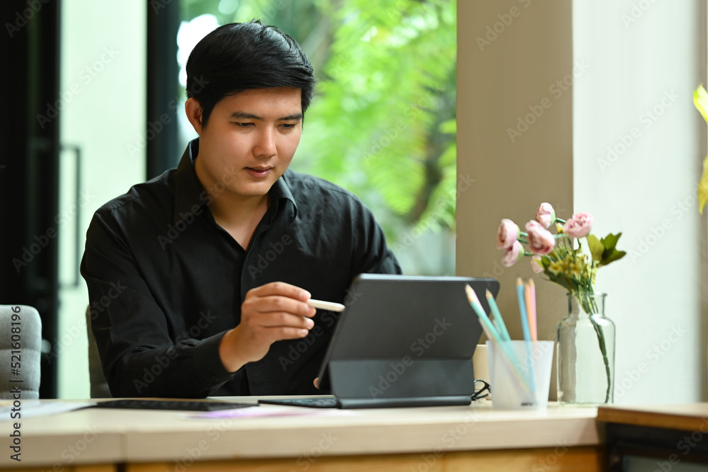 Young entrepreneur working with digital tablet for making new designs at start up office Young entrepreneur working with digital tablet for making new designs at start up office