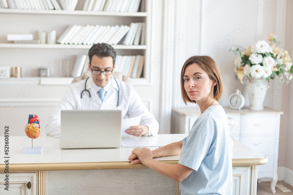 Portrait of young female patient and doctor cardiologist working in office of modern clinic Portrait of young female patient and doctor cardiologist working in office of modern clinic