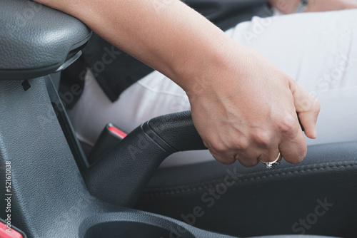 Close-up of a woman's hand pulling handbrake lever in the car. Woman is driving a car. Emergency braking.