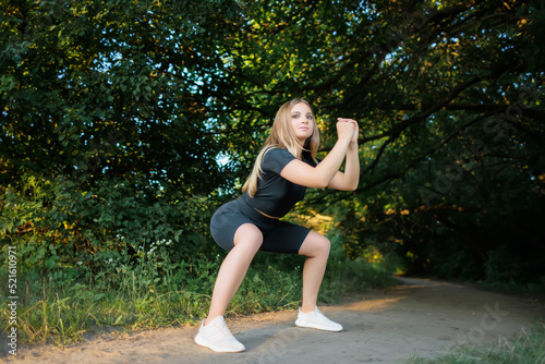 girl fitness model goes in for sports in the park doing squats © Roman