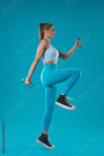 A girl trainer in blue sportswear doing an aerobics movement on a blue background.