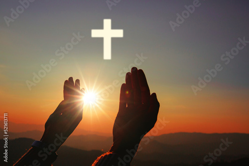 Silhouette of human hands palm up praying and worship of cross, eucharist therapy bless god helping, belief, forgiveness, freedom, hope and faith, christian religion concept on sunset background.