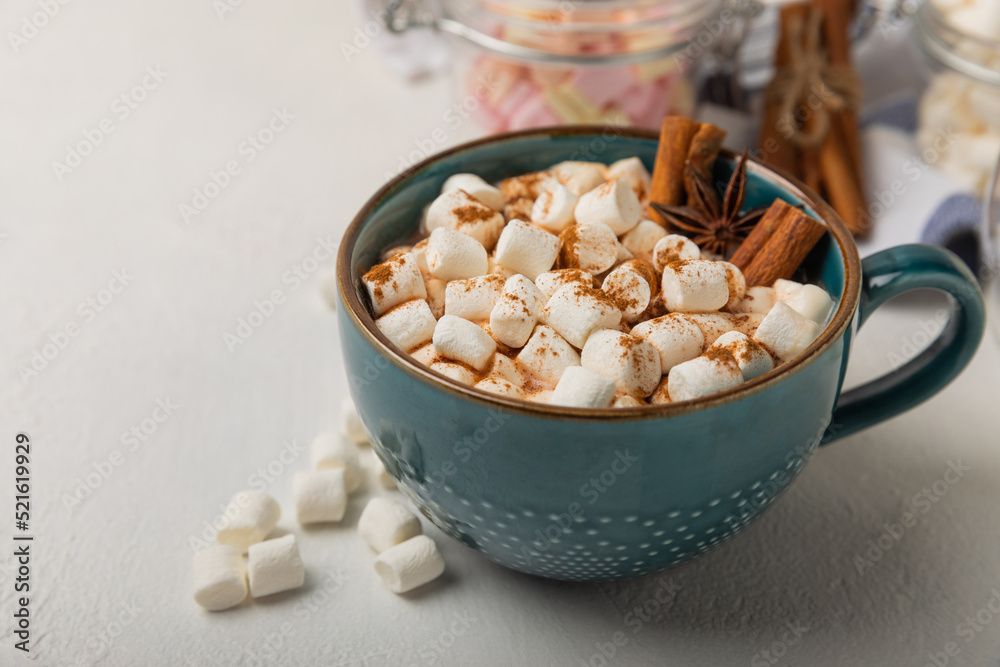 Cup of tasty cocoa drink and marshmallows in blue cup.Spices and marshmallows for winter drinks on white texture table.Winter hot drink.Hot chocolate with marshmallow and spices.Copy space. Cup of tasty cocoa drink and marshmallows in blue cup.Spices and marshmallows for winter drinks on white texture table.Winter hot drink.Hot chocolate with marshmallow and spices.Copy space.