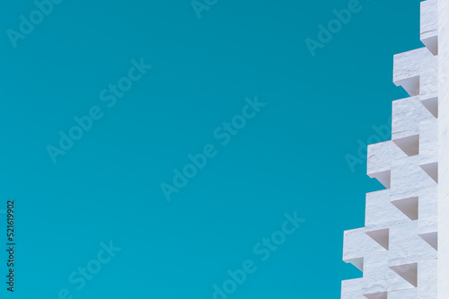 Geometric white apartment block diagonal geometric balconies against a bright turquoise sky