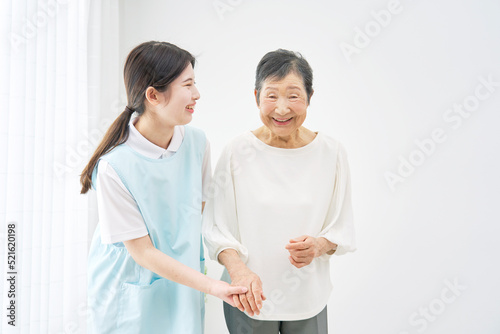 介護施設でシニア女性に寄り添って歩く介護士