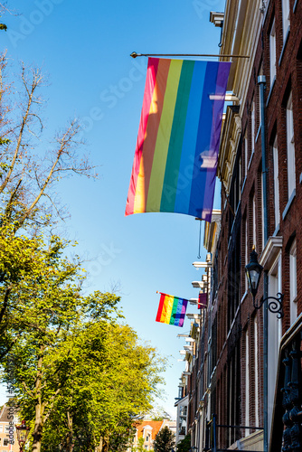 Old Dutch canal houses in Amsterdam with a Progress Pride Flag on their facades during Gay Pride Amsterdam, The Netherlands, Europe