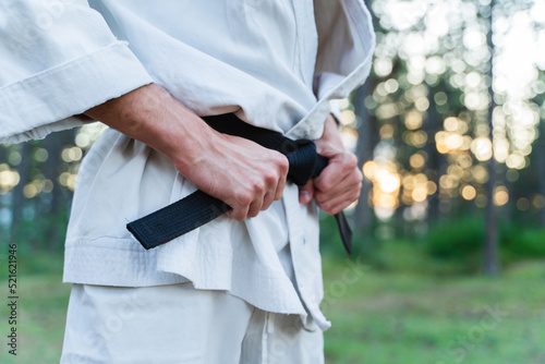 A young guy doing karate training and meditation in the forest during the day