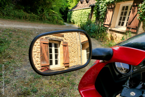 French country cottage reflected in a motorbike wing mirror, parked outside of a French farmhouse
