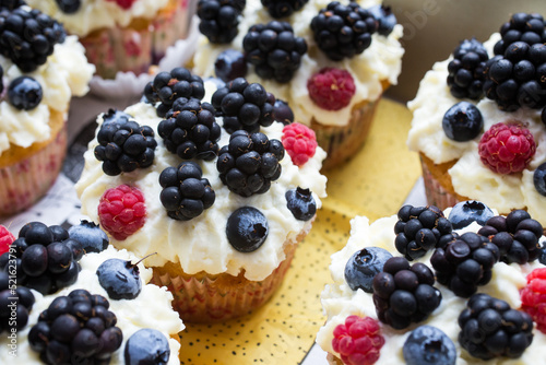 Homemade cupcakes decorated white cream and wild berries, delicious and fresh,