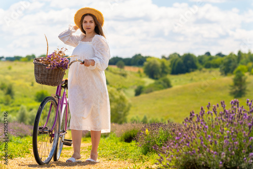 Young woman in a lacey white summer dress pushing her bike