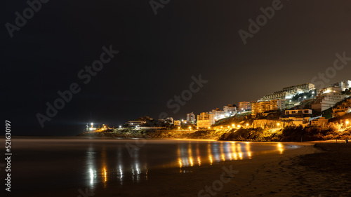 view of a coastal town at night with reflections in the water